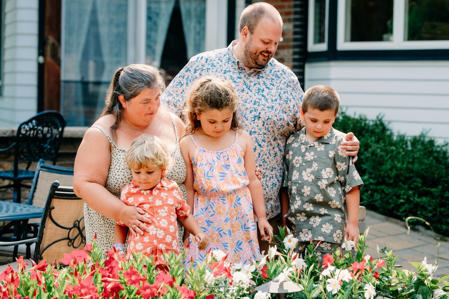 Family of five standing together for portrait, flowers in foreground.