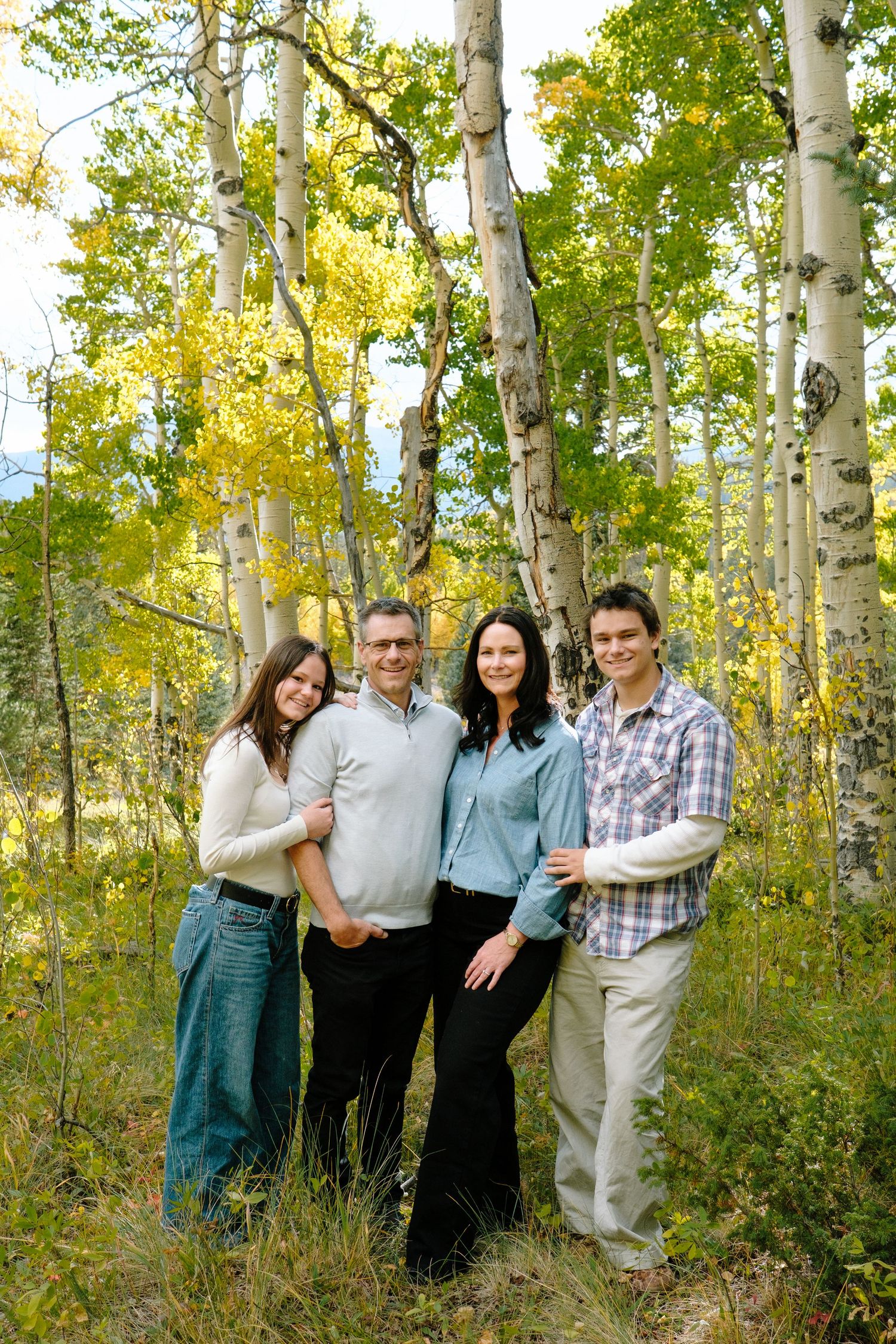 Family with teenagers in Colorado mountains, yellow aspens in background.