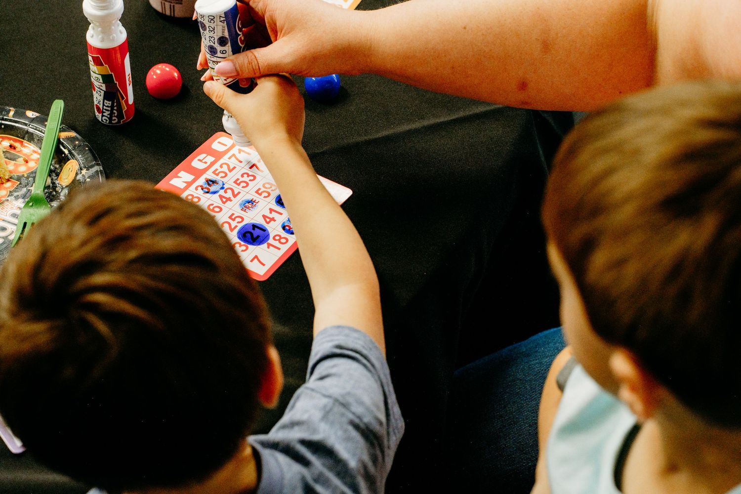 Overhead view of young boys dabbing bingo numbers with bingo markers.
