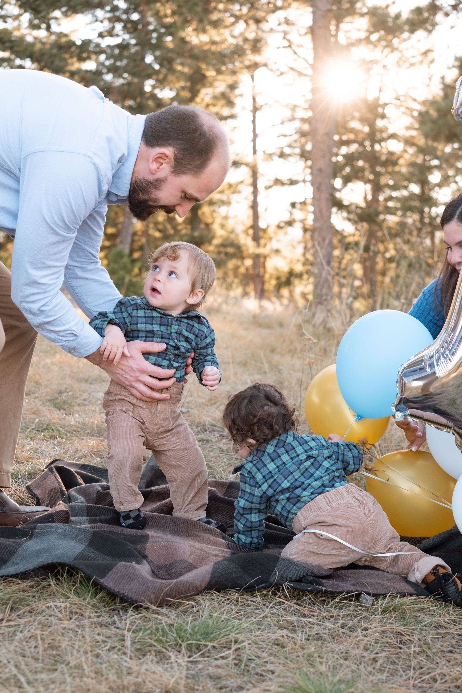 Mother and father coraling one year old milestone portraits of two twin boys with balloons in the forest area of Mt Falcon West.