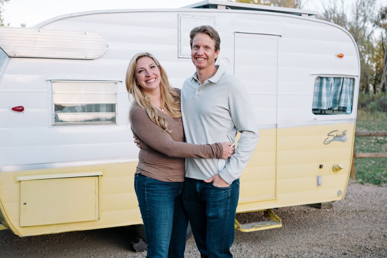 Close up of husband and wife in front of vintage Shasta trailer at Bear Creek Lake Park in Lakewood, Colorado.