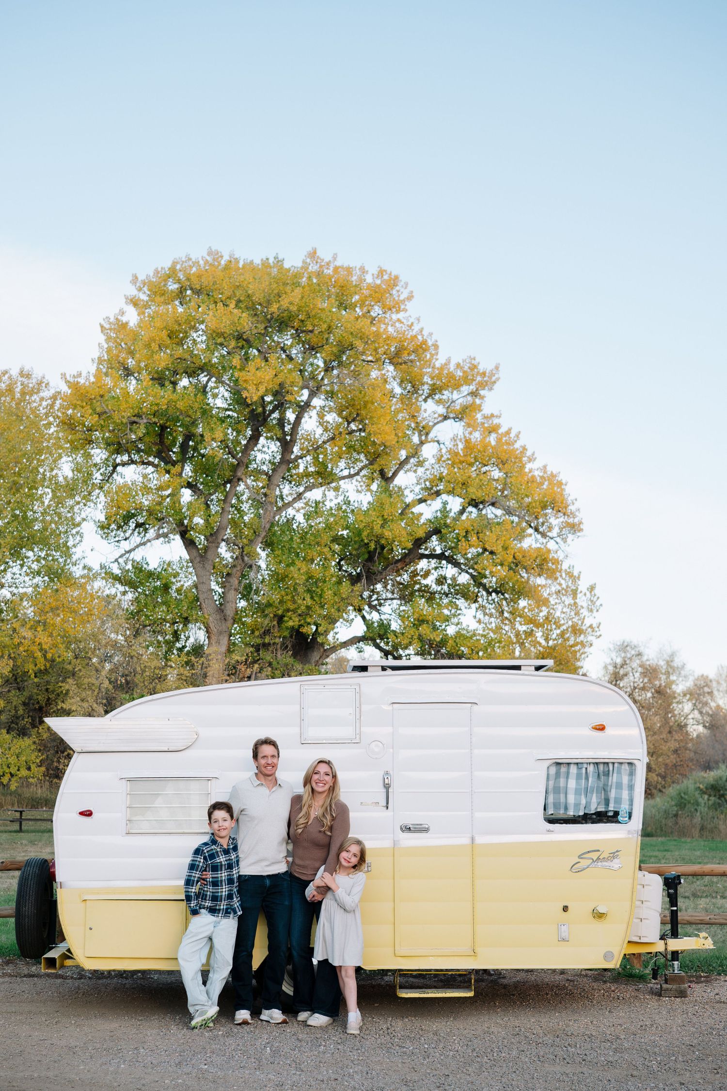 Family of mother, father and two children in front of vintage Shasta trailer at Bear Creek Lake Park in Lakewood, Colorado.