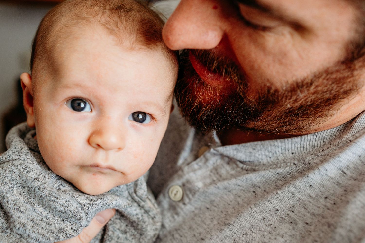 Close up of father and baby son's face, father looking at newborn, newborn gazing calmly.