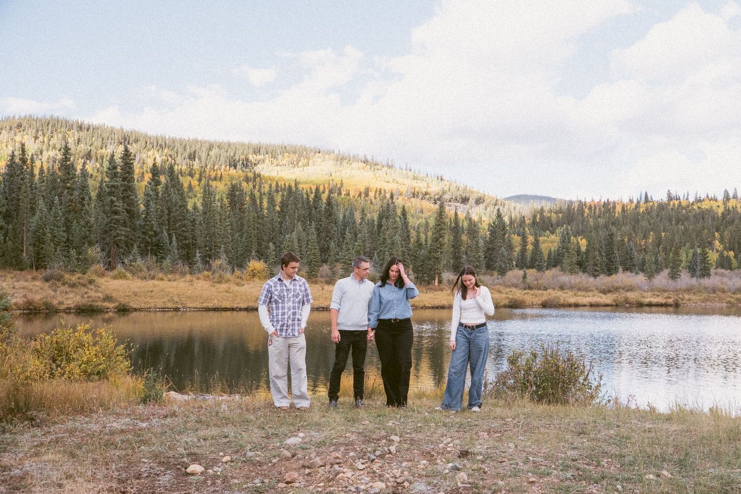 Candid of family of fur standing in front of pond in Colorado mountains.
