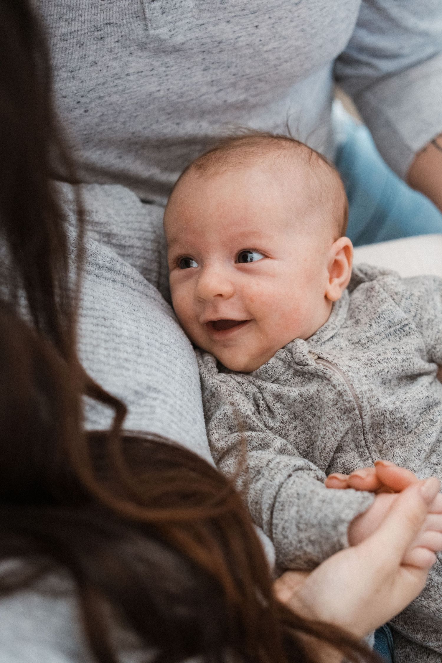 Newborn boy being held in mother's arms, smiling up at mother.