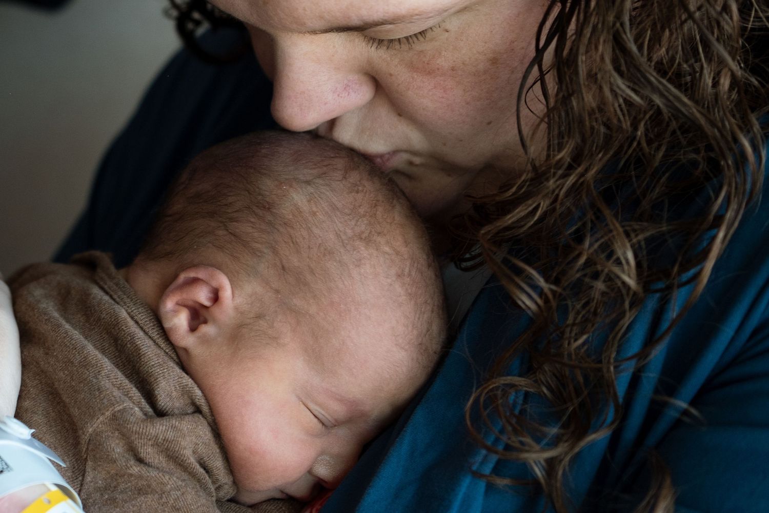 Close up of mother kissing brand new baby's head.