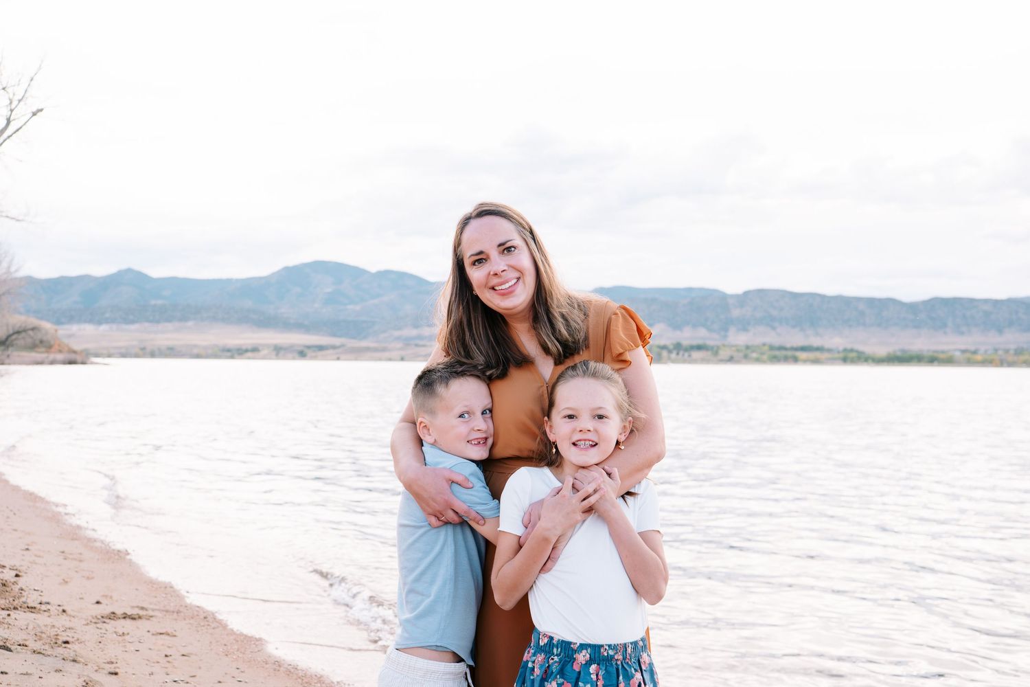 Mother embracing two children, foothills and Chatfield reservoir in background.