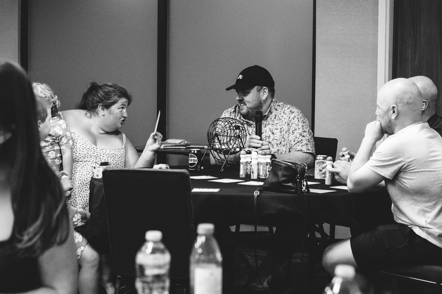 Black and white portrait of family engaging in playfully competitive bingo game in celebration of Grandma's 90th birthday party.