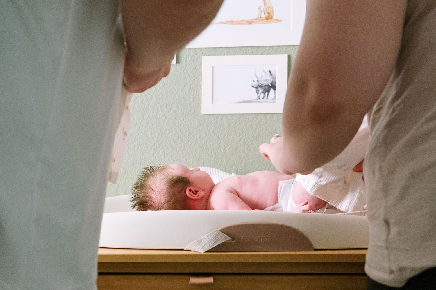 Mother and father changing baby on changing mat in nursery during Denver in-home photo session.