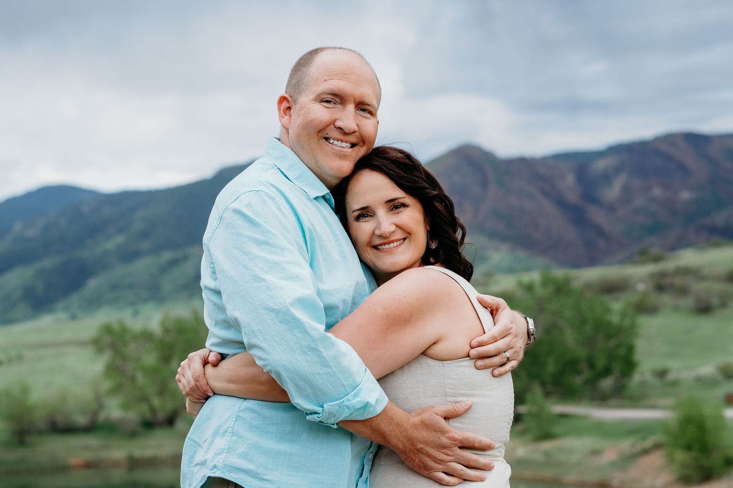 Mother and father embracing, foothills in background.