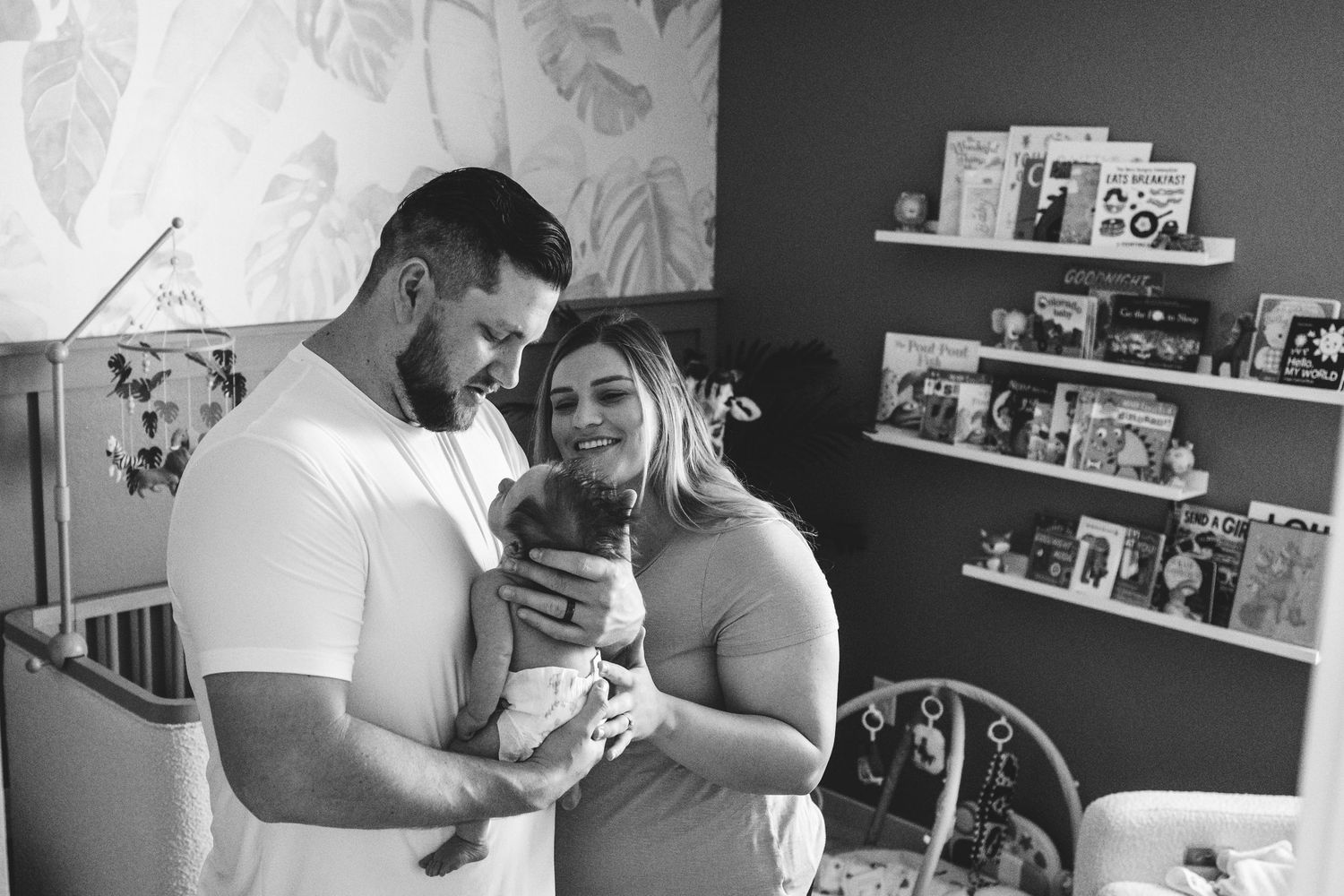 Black and white of mother and father holding newborn boy in newborn's nursery during Denver in-home photo session.