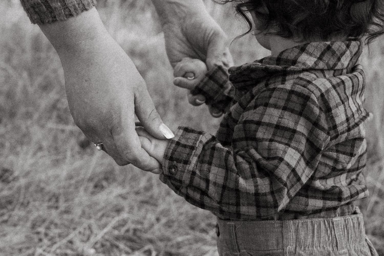 Black and white of mother holding one year old toddler boy's hands.