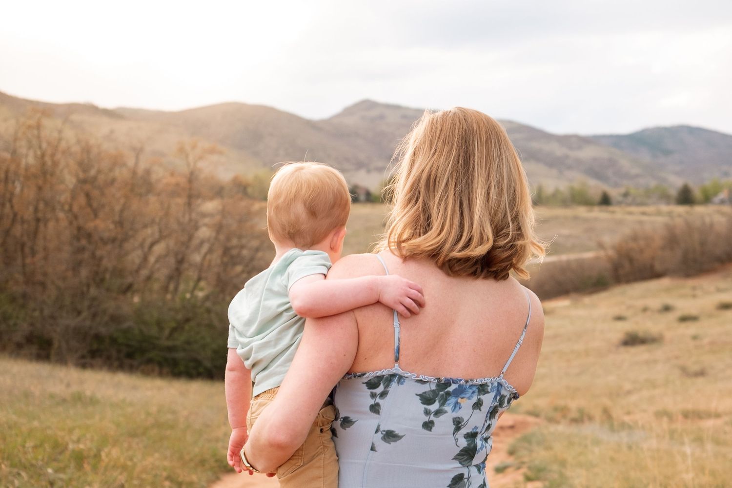 Mother holding toddler son, stunning landscape in the background.