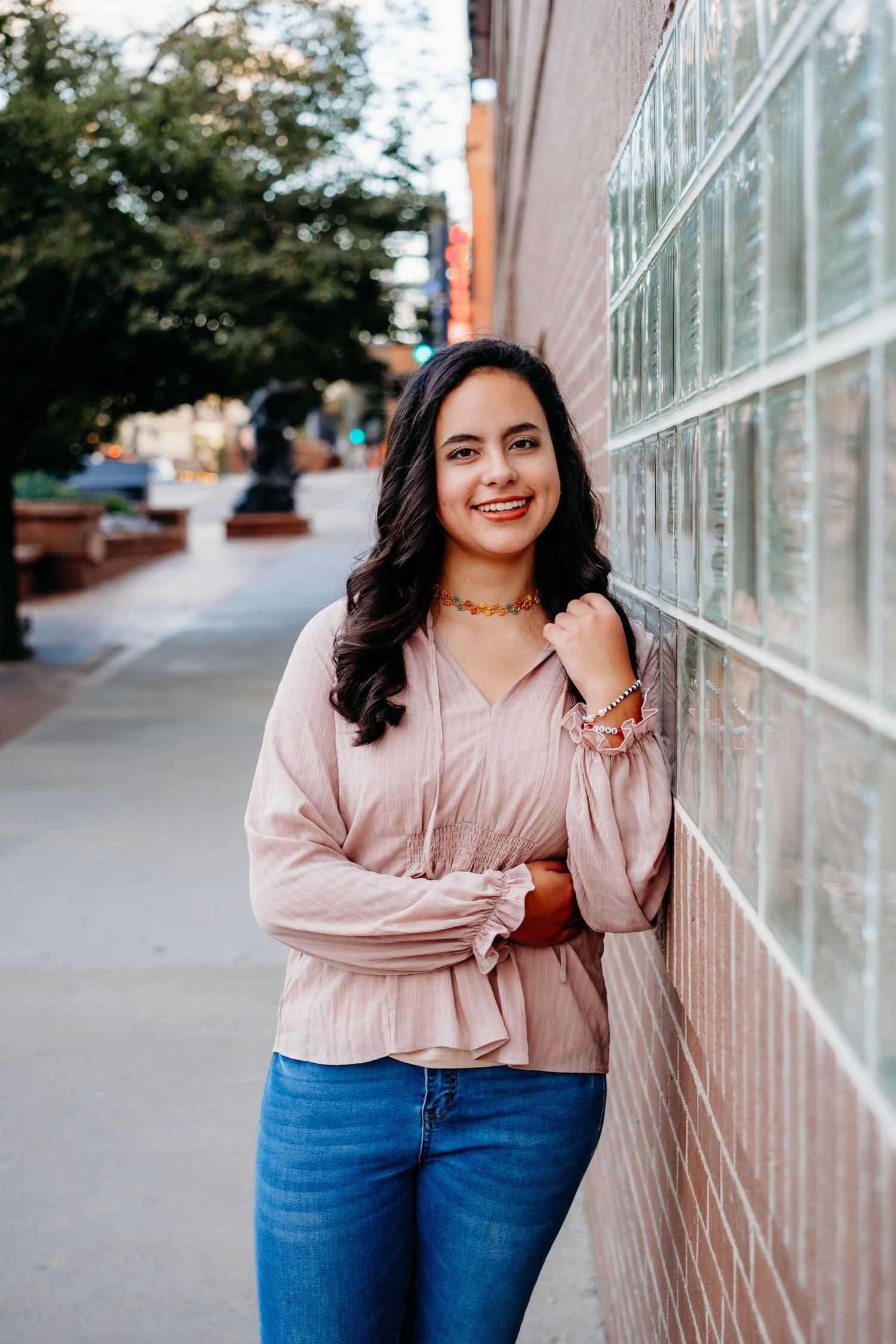 Senior portrait of girl smiling, leaning against brick wall, in Golden, Colorado.