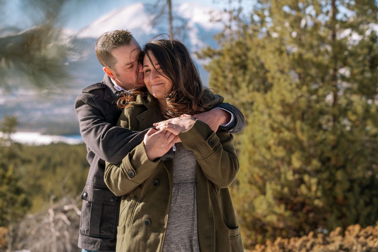 Newly engaged couple embracing, man hugging woman from behind over her shoulders near Breckenridge, Colorado during engagement photo session