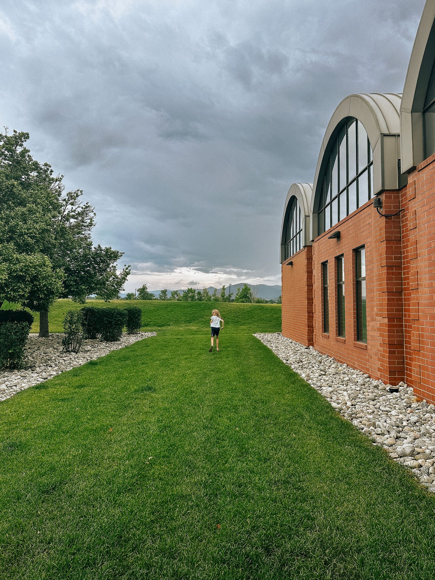 Denver photographer's project 365, June, girl running down green strip of grass in front of library.
