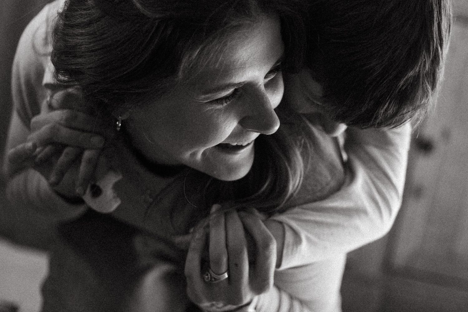 Documentary photo of son holding on to mother's back, mother holding onto son's arms in a bear hug.