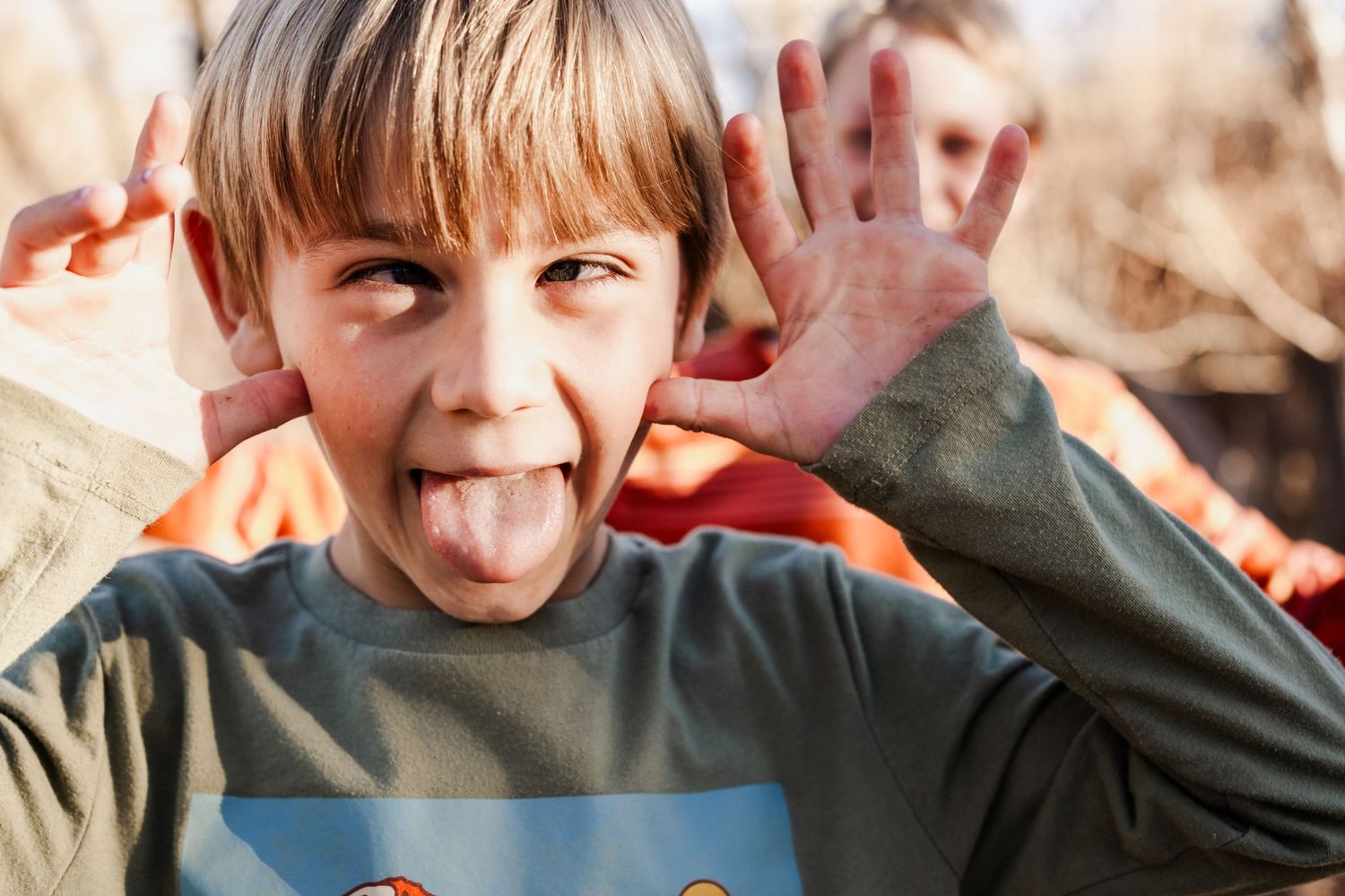 Playful portrait of young boy making silly fa beside the creek at Matthews / Winter Park in Golden, Colorado, during a family photo session.