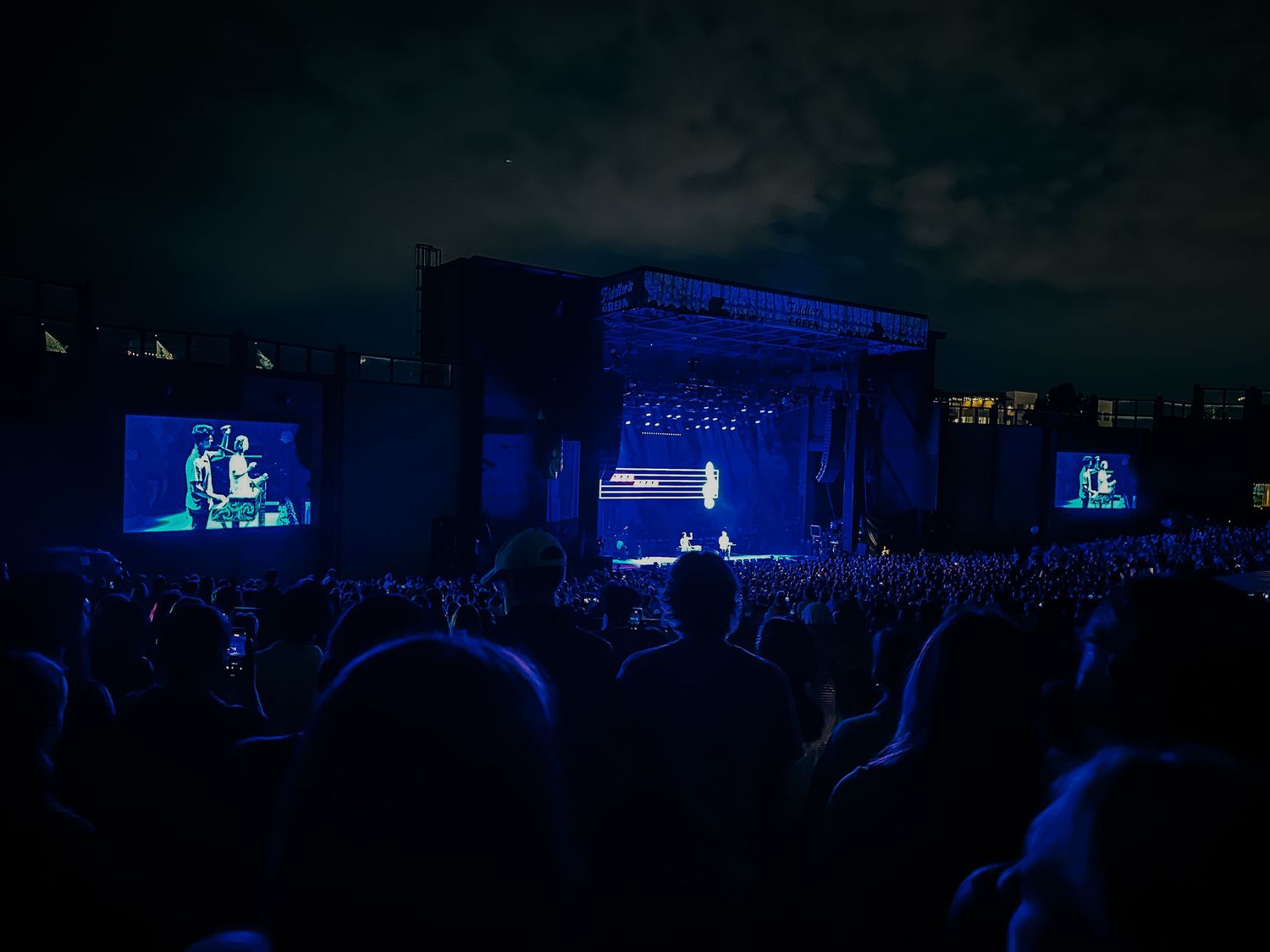 Dark stage portrait of AJR concert.