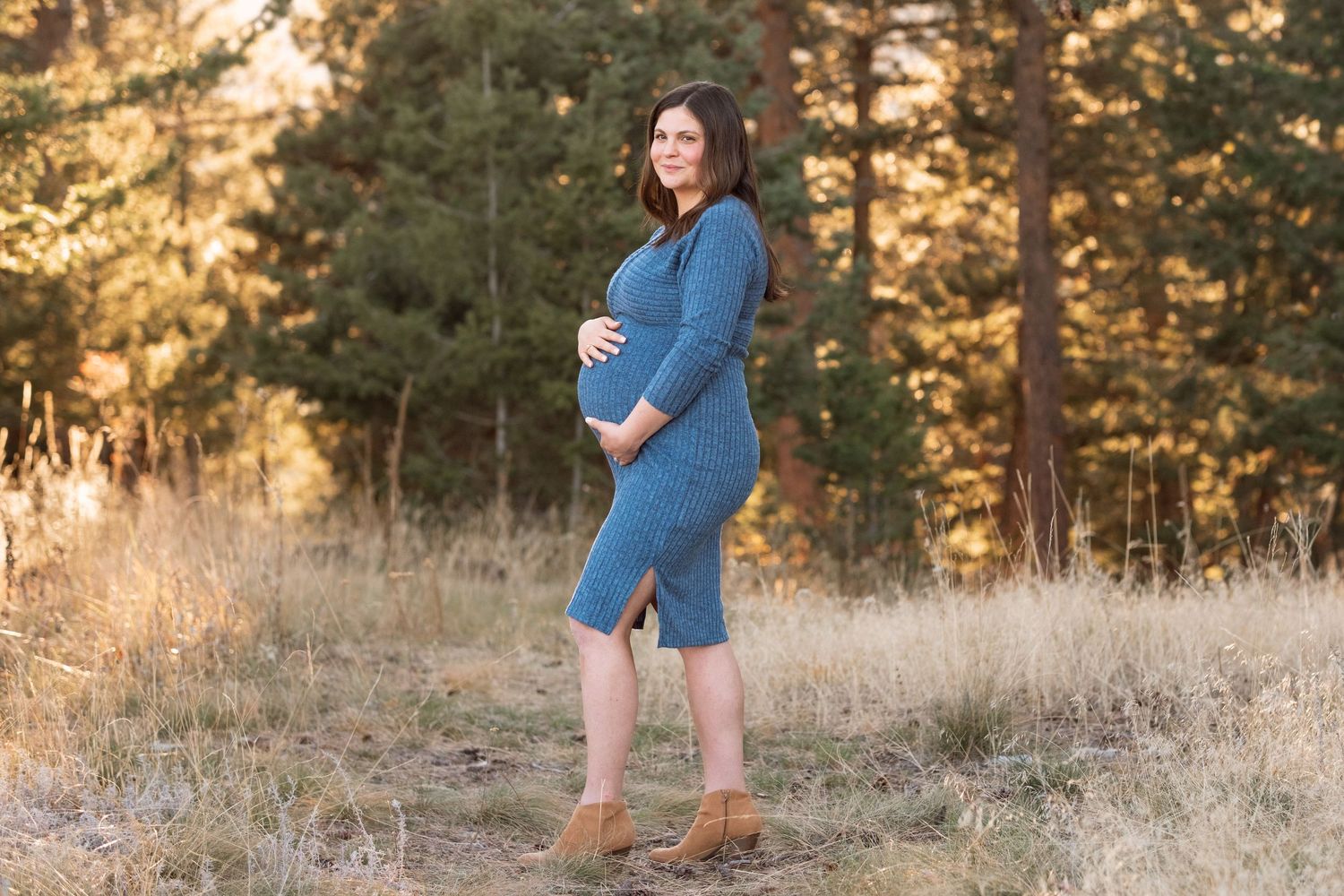 Maternity portrait of pregnant mother's profile as she holds her belly, wearing a blue dress at Mt Falcon West.