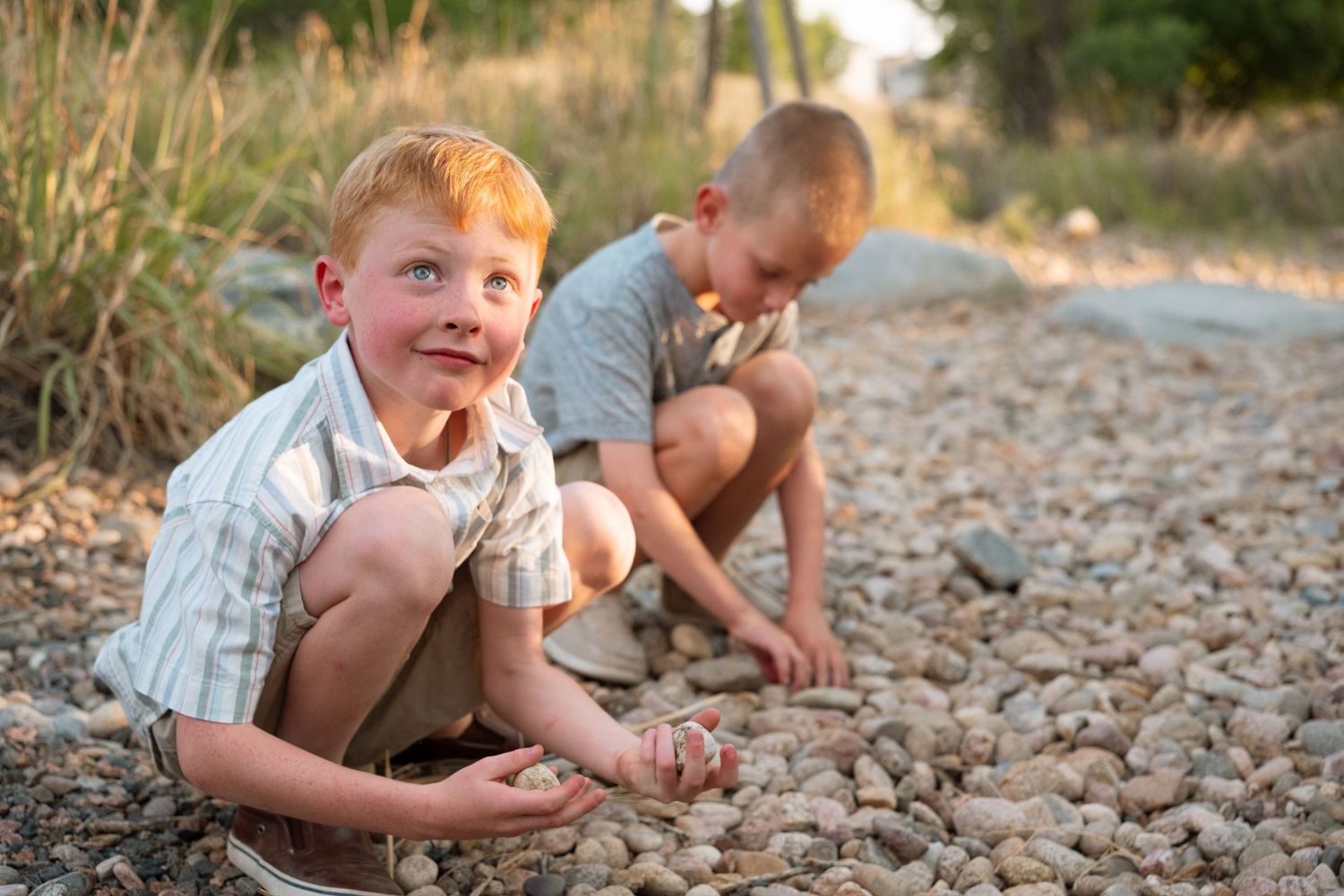 Two boys playing in rock bed during extended family photo session.