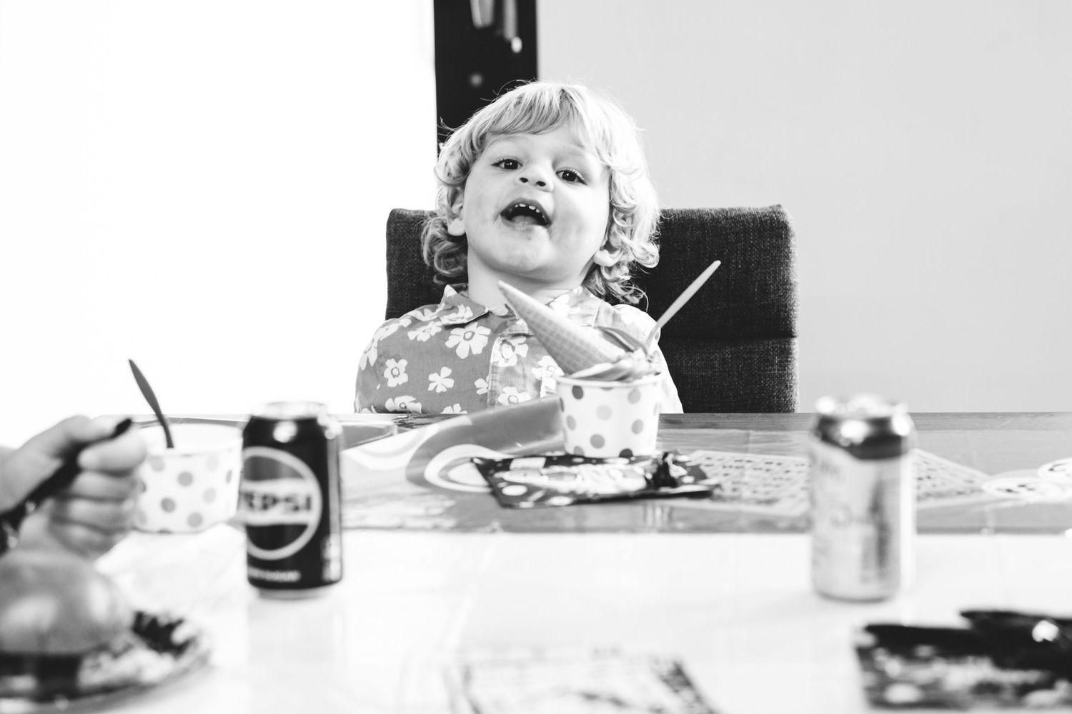 Black and white of young boy sitting with large ice cream cone.
