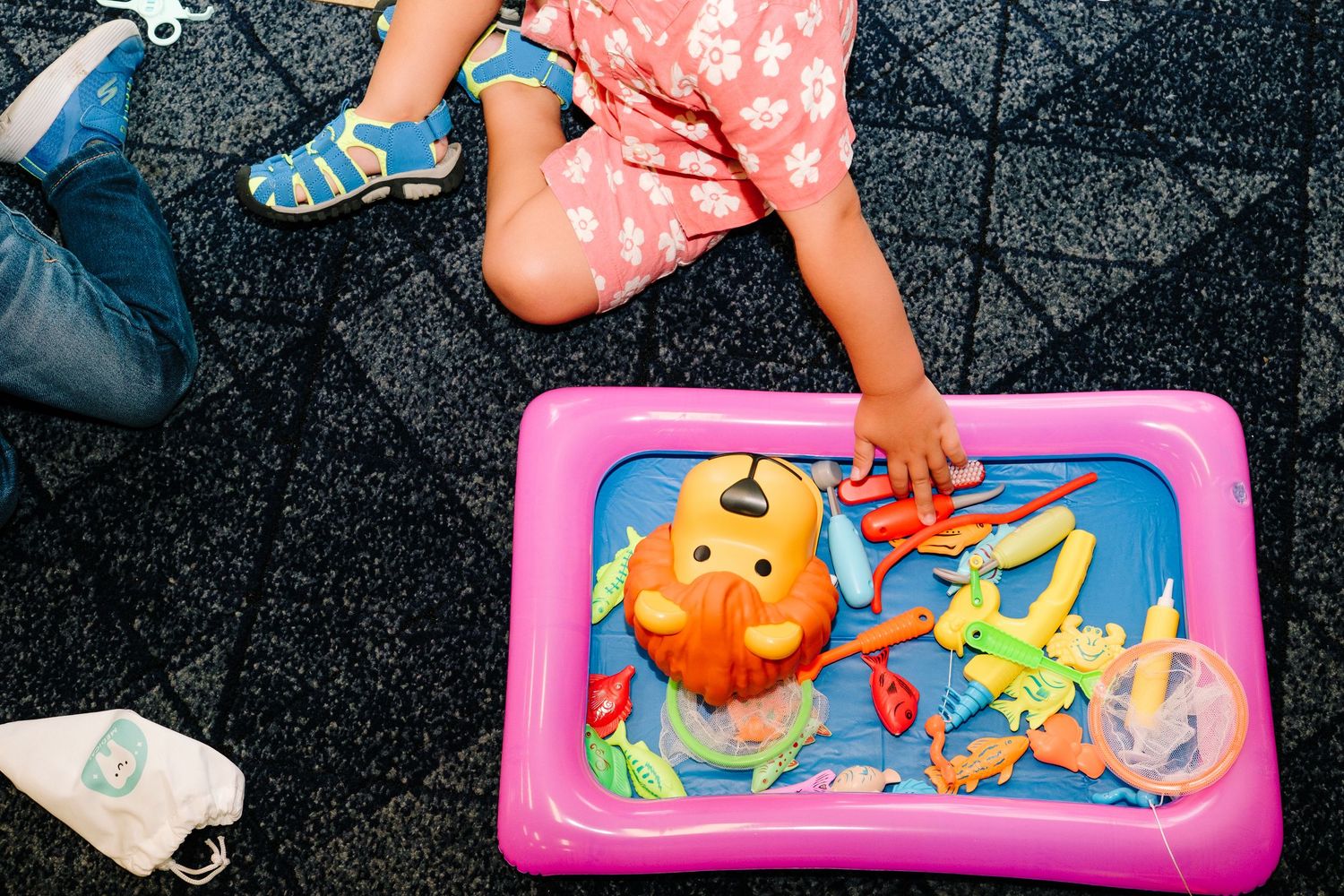 Overhead view of young boy playing with brightly colored fishig toy.