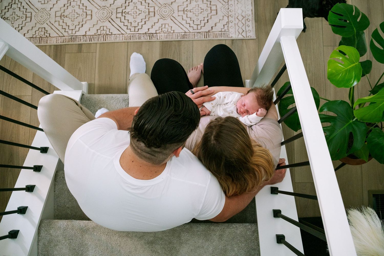 Overhead view of mother and father sitting on stair steps, mother holding newborn boy.