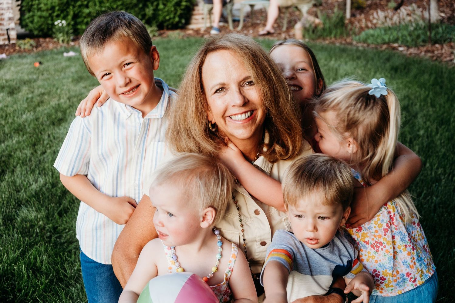 Grandma being snuggled by five grand kids of various ages.