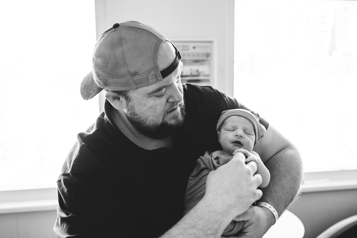 Father holding newborn, gazing lovingly at baby.