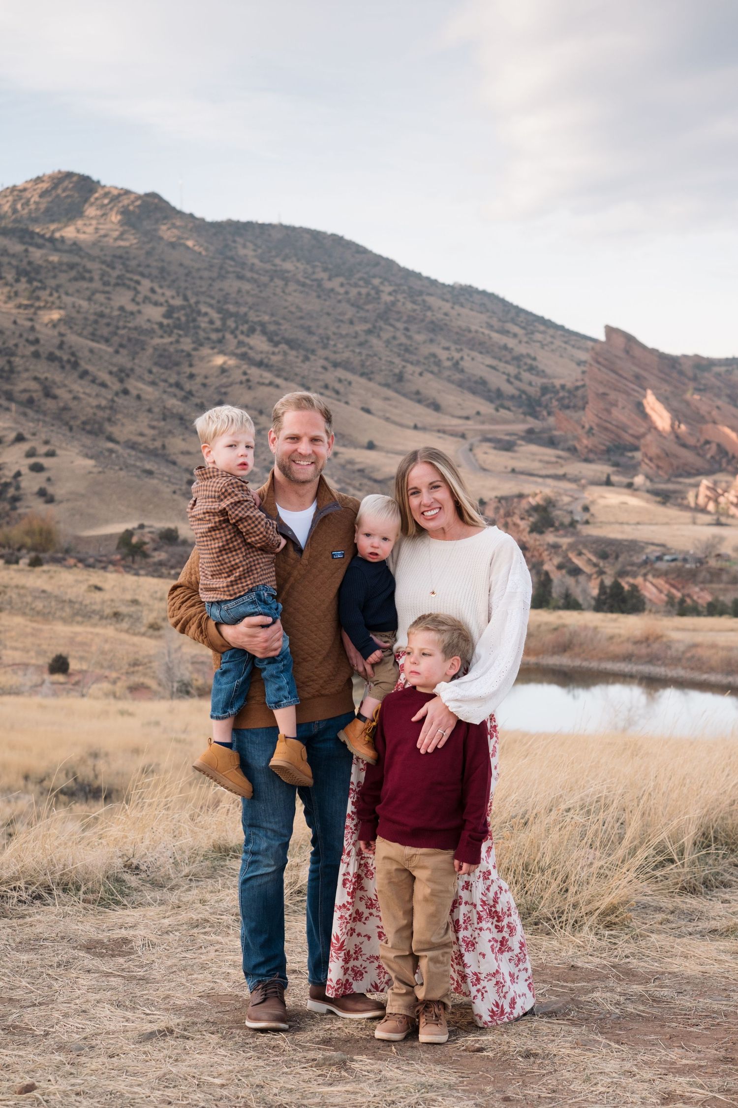 Family portrat of mother, father and three young sons standing at Mt Falcon East with Red Rocks views in the background in Morrison, Colorad