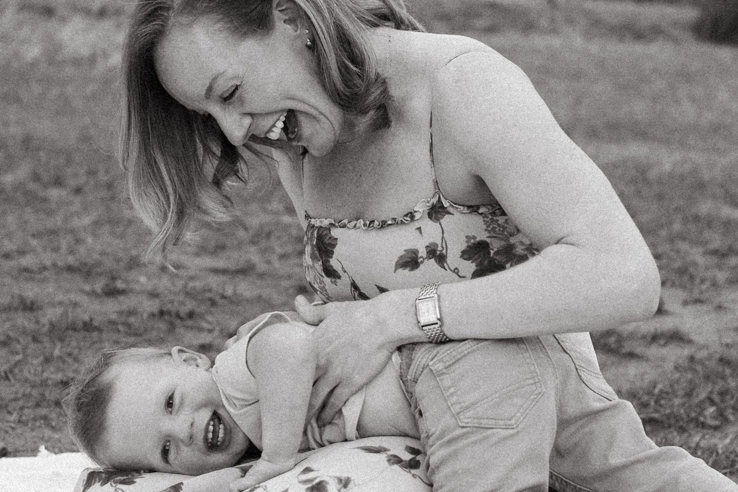Black and white of mother tickling toddler son.