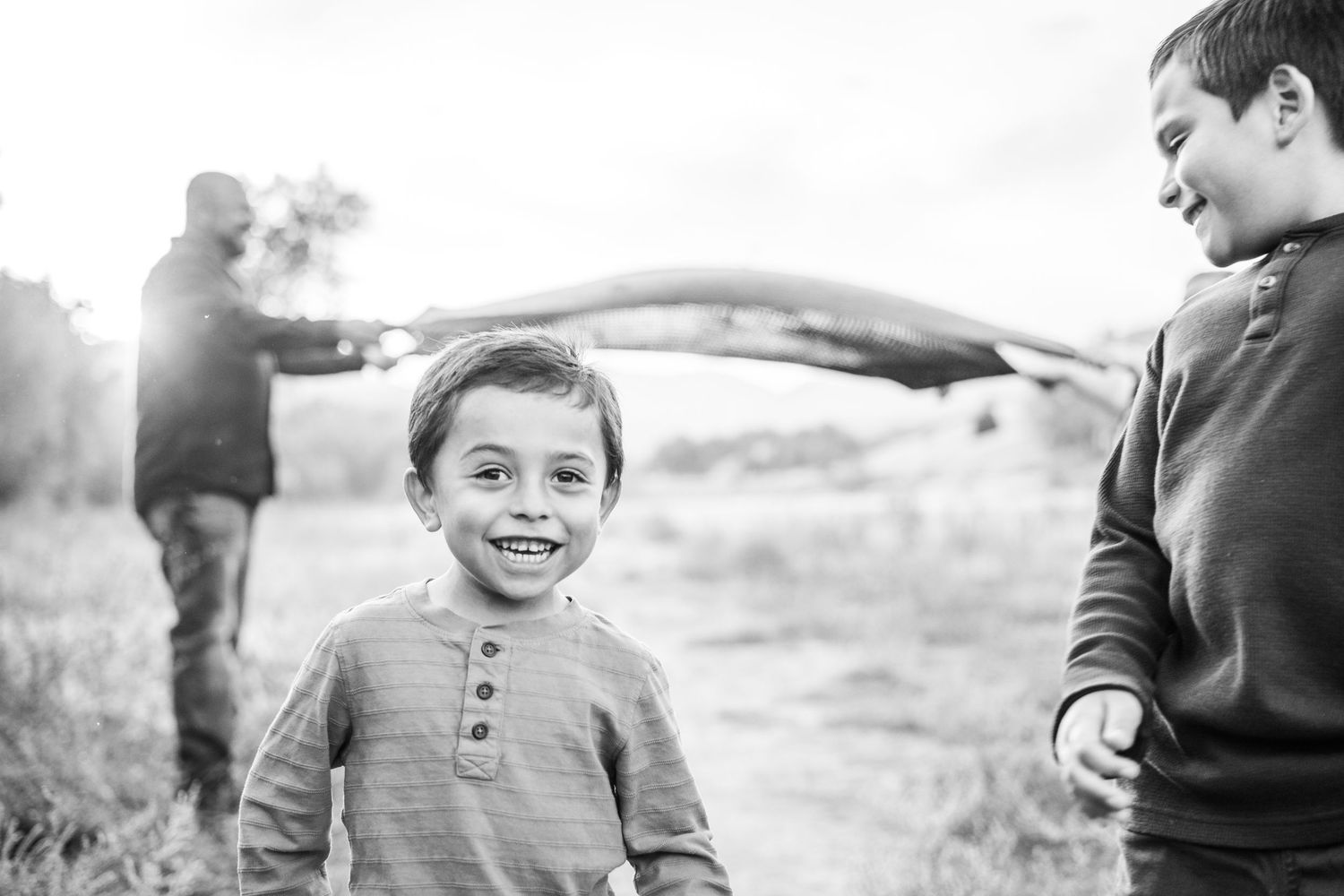 Brothers playfully running and laughing at Bear Creek Lake Park in Lakewood, Colorado.