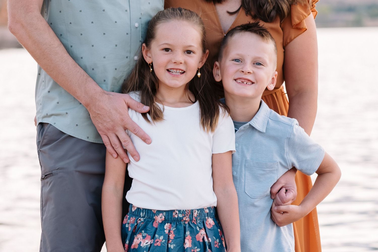 Family photo session at Chatfield State Park, close up of brother and sister, lake in background.