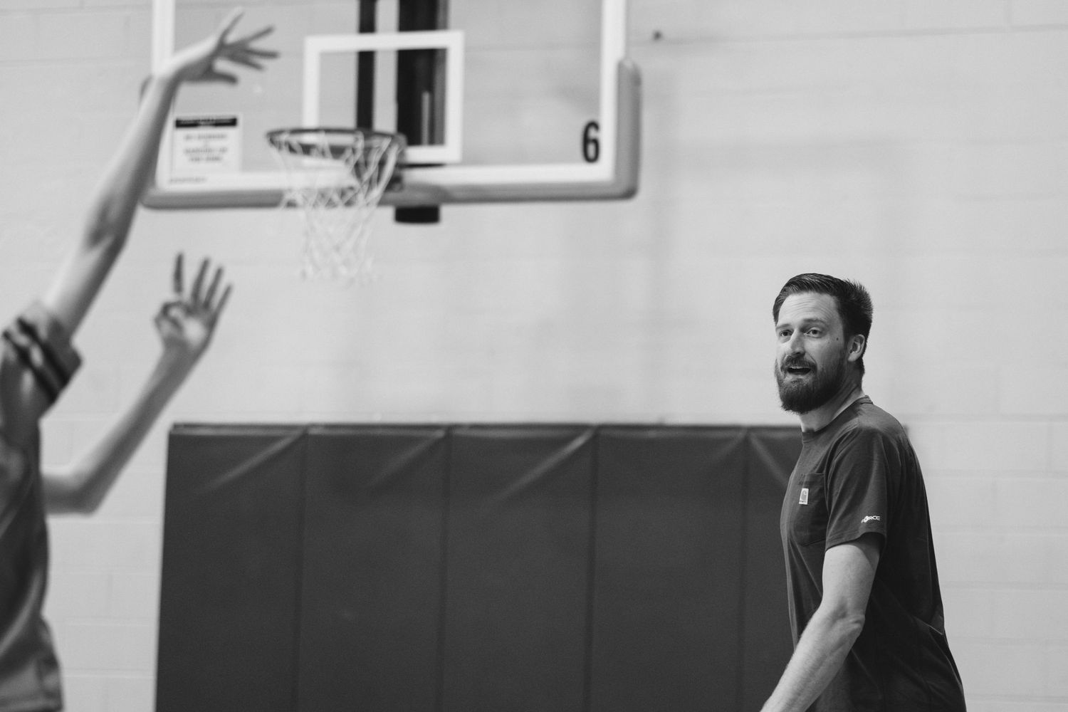 Basketball coach gazing toward player making a shot.