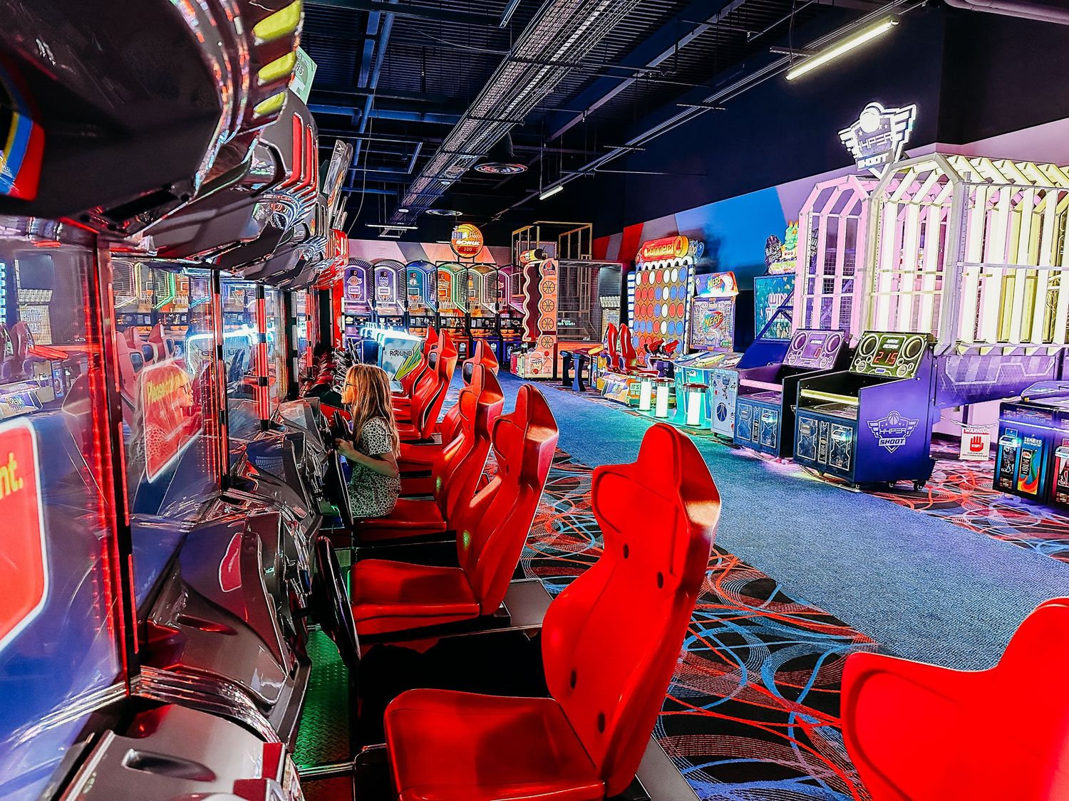 Vibrant photo of an arcade, lots of red racing games.