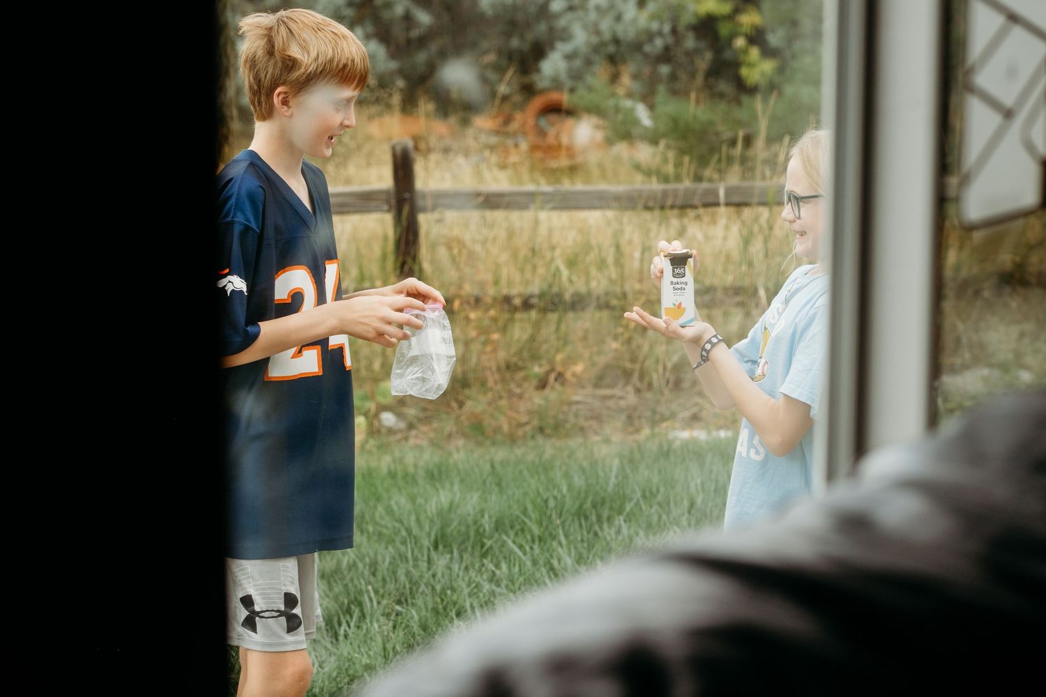 Project 365 photo - through the window shot of two children playing in backyard.