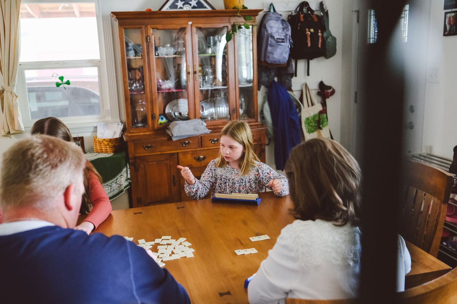 In-home Denver family photography session,  family of four playing rumikub at dining table.