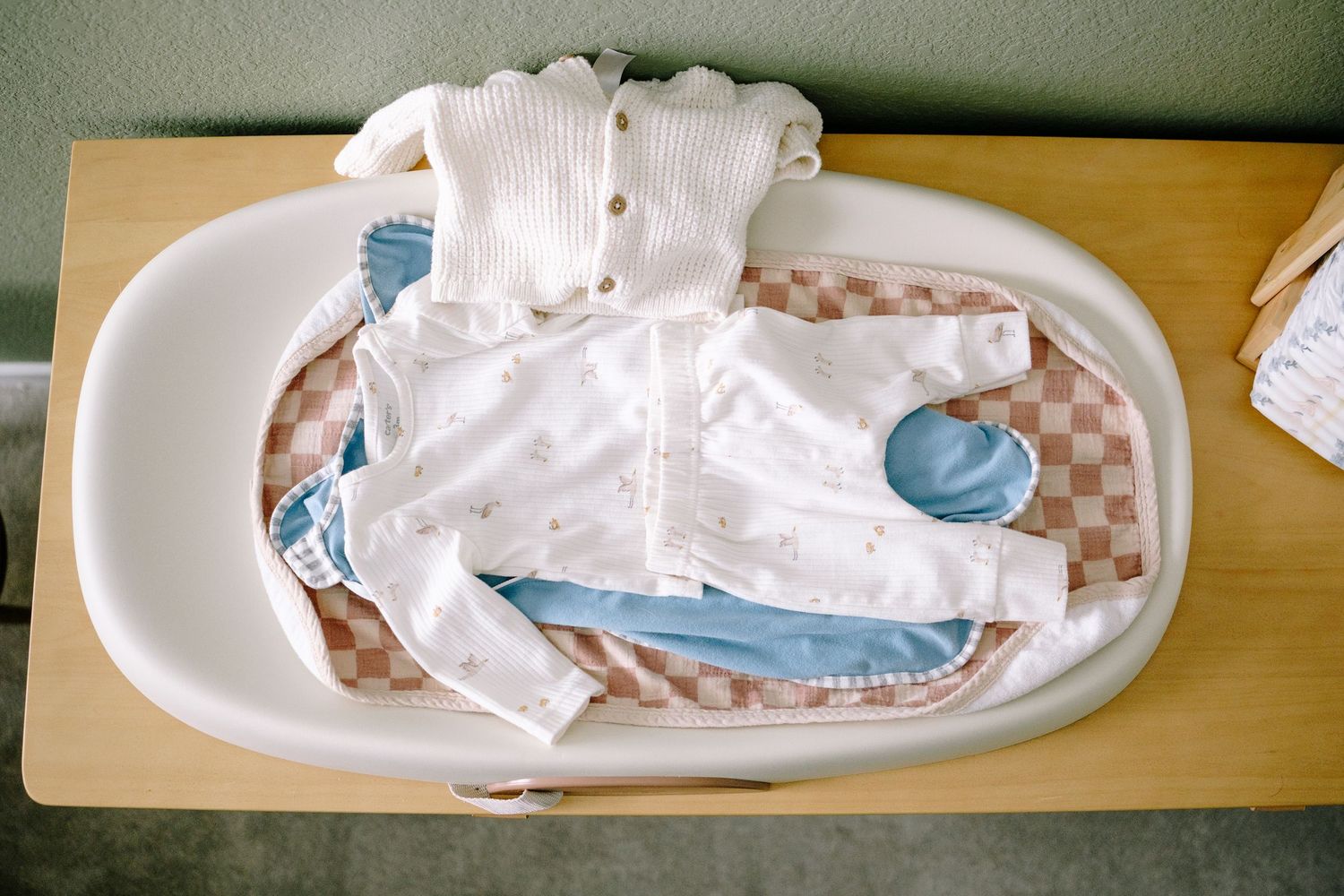 Flat lay of newborn outfit on changing mat on changing table in newborn nursery.