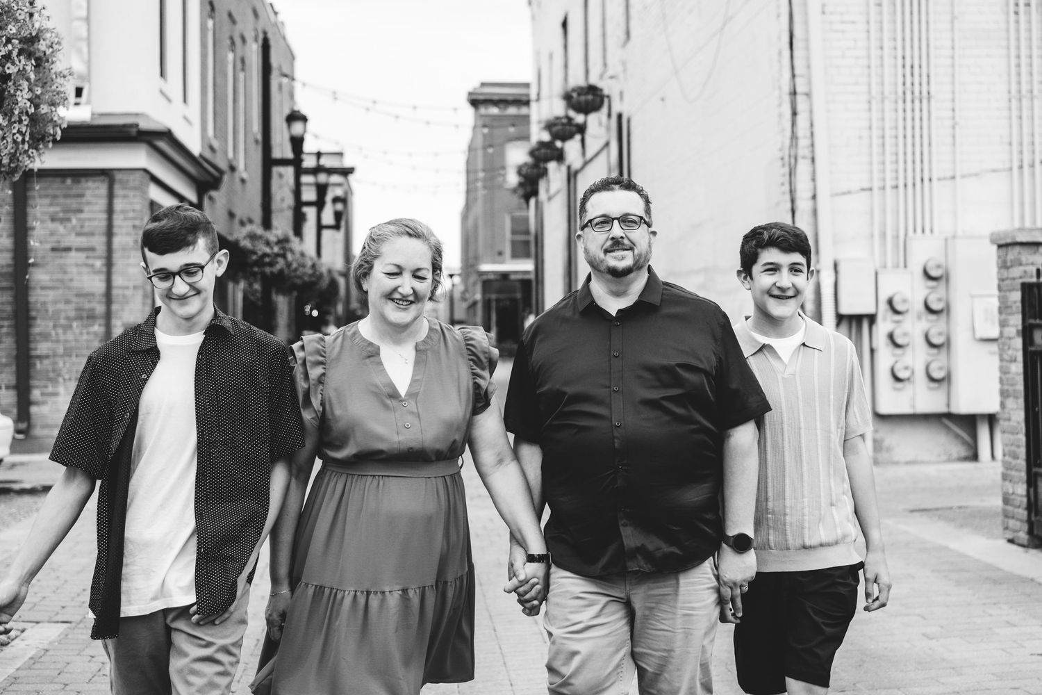 Black and white of family of four, including two teen boys, walking down alleyway in Fort Collins.