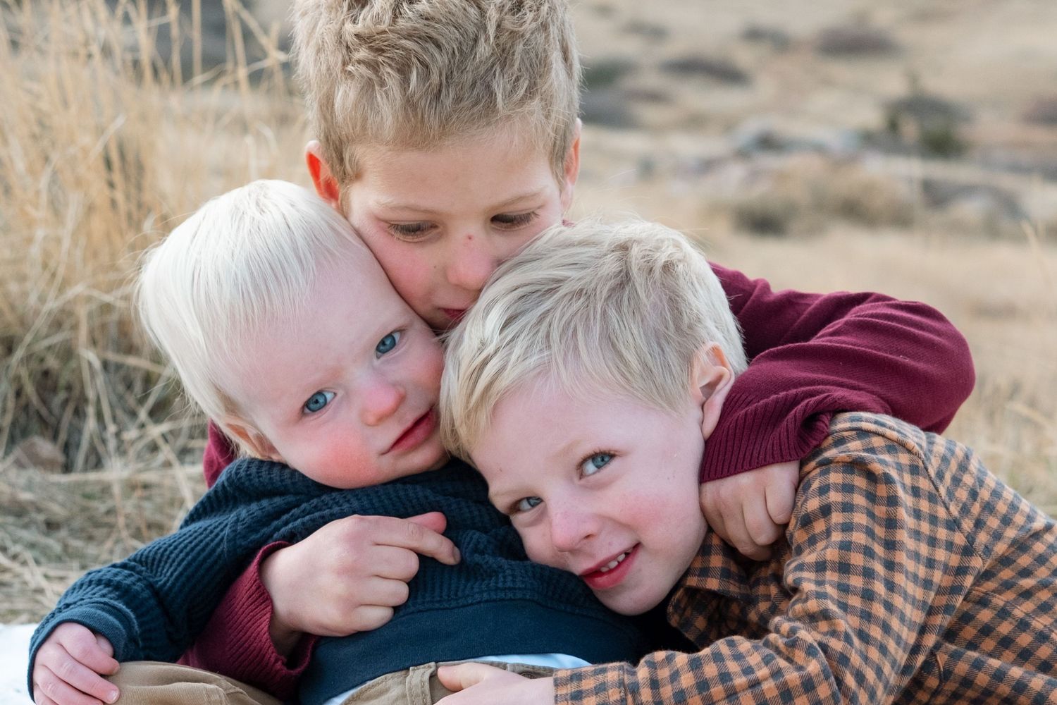 Oldest brother holding two younger brothers close for a tight hug.