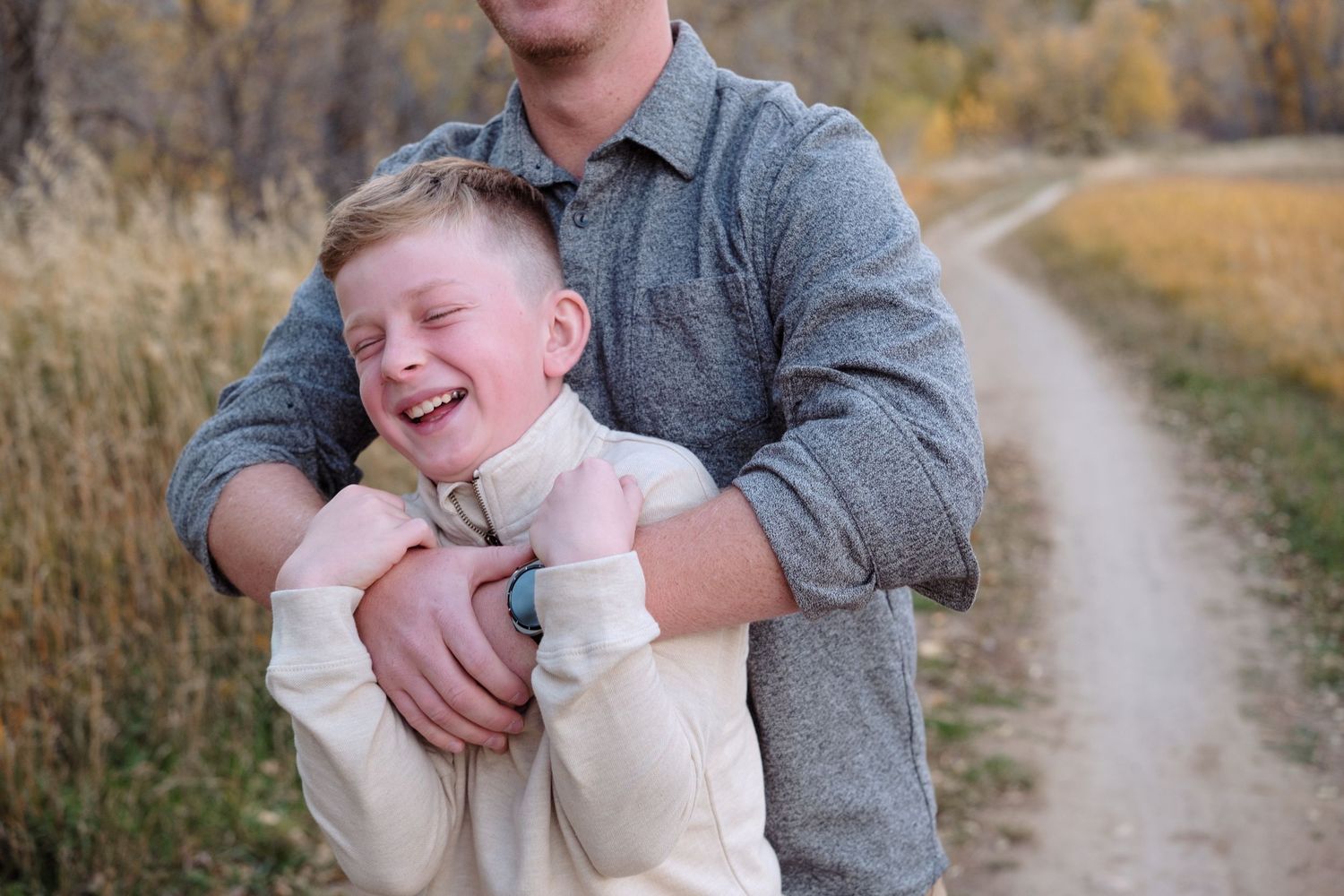 Father playfully holding son, son laughing.