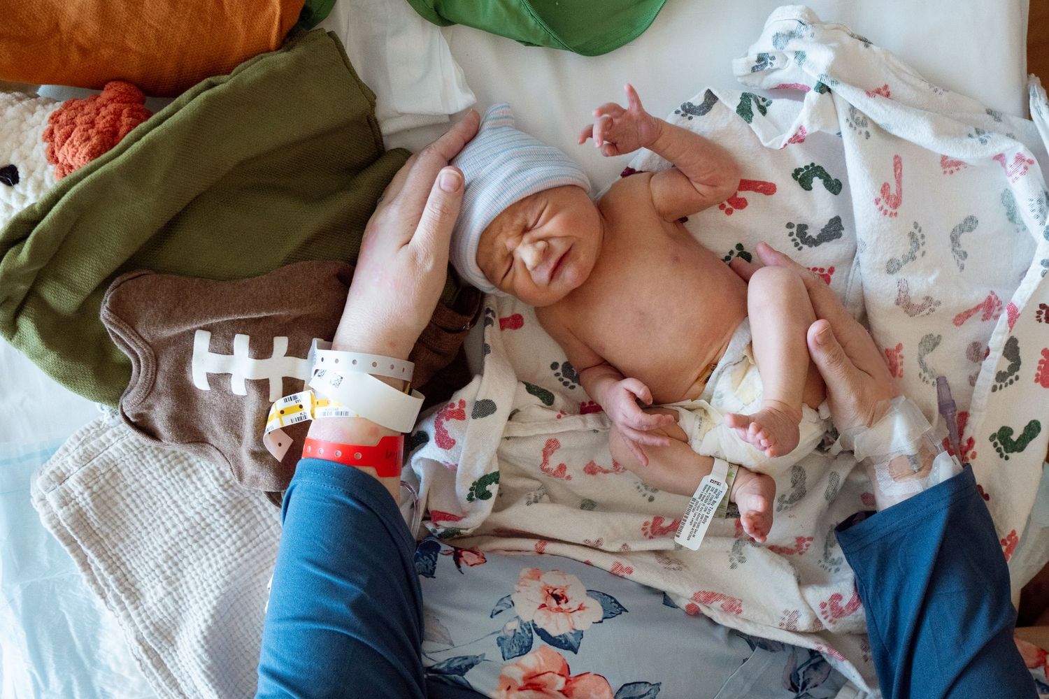 Overhead photo of newborn baby in diaper, being unswaddled and about to be dressed.