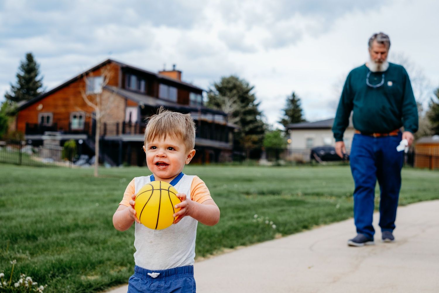 Denver photographer's project 365, May, young boy holding yellow ball walking on path at neighborhood park, grandfather following behind.