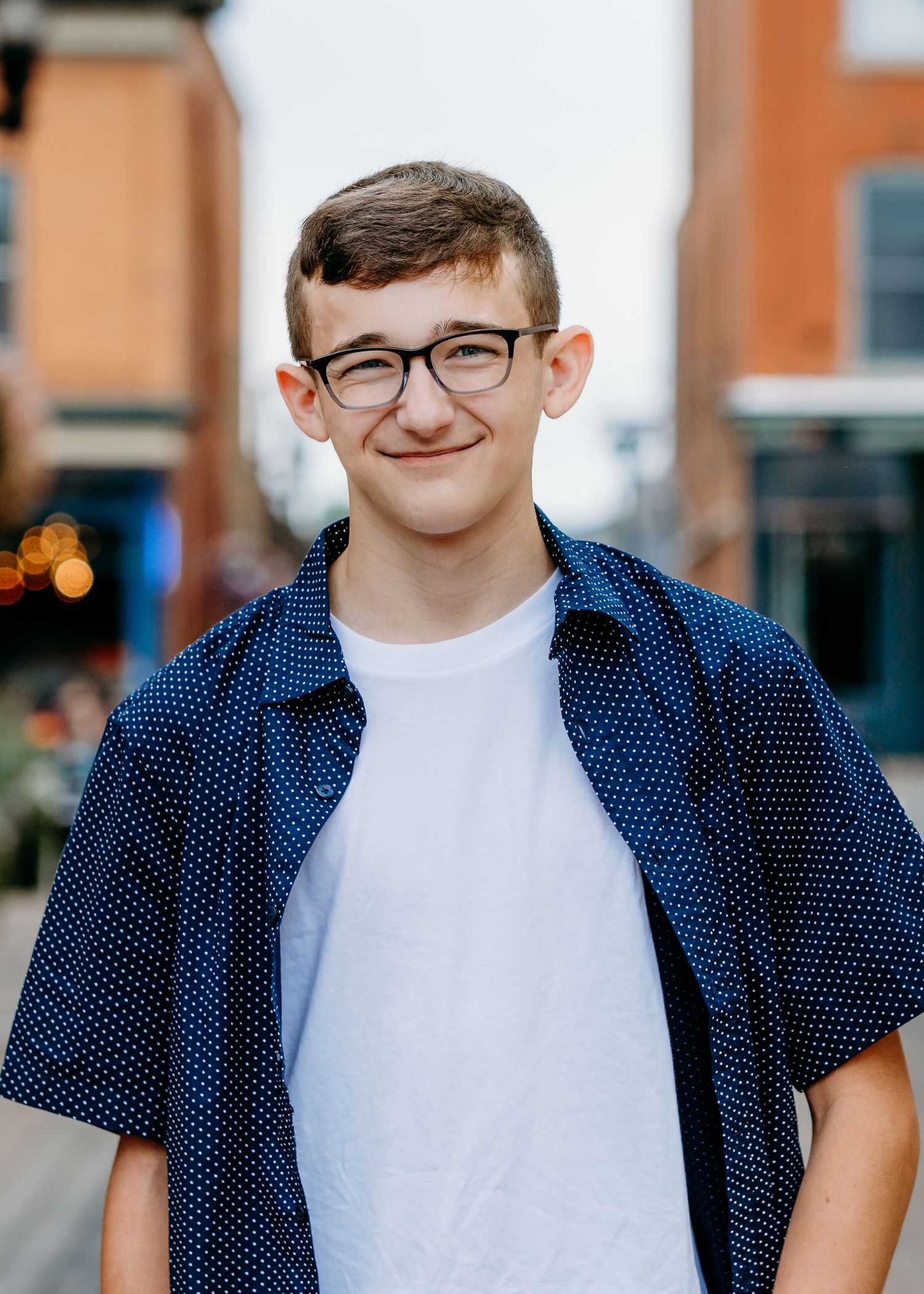 Senior portrait of a teen boy walking through a charming alley in downtown Fort Collins, featuring brick buildings.