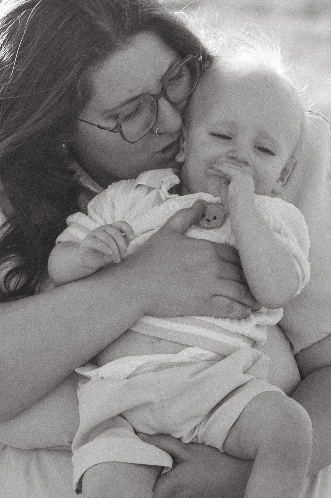 Black and white portrait of mother kissing cheek of toddler son.