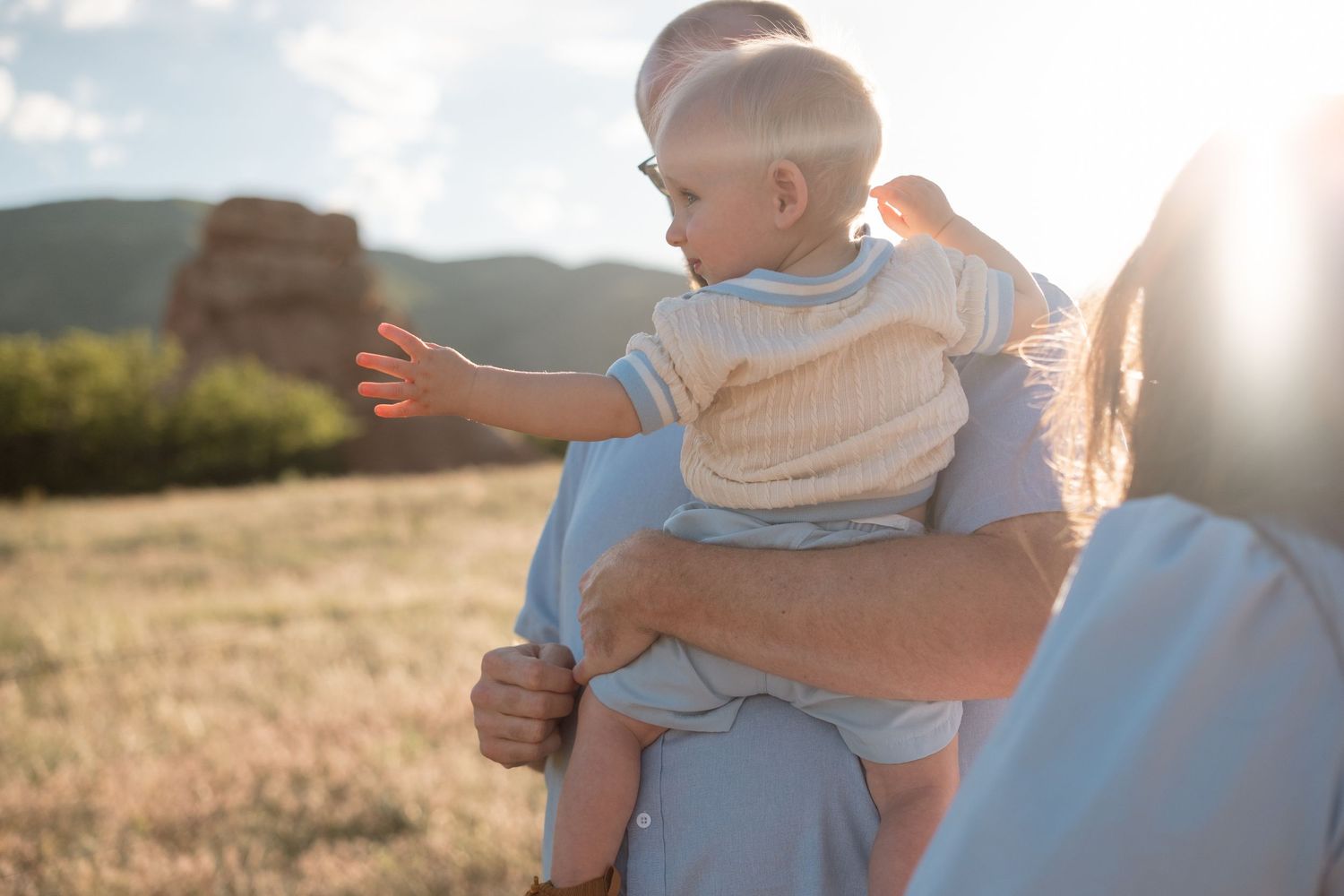 Father holding son, walking at at South Valley Park in Littleton, Colorado, mother in foreground looking toward them.