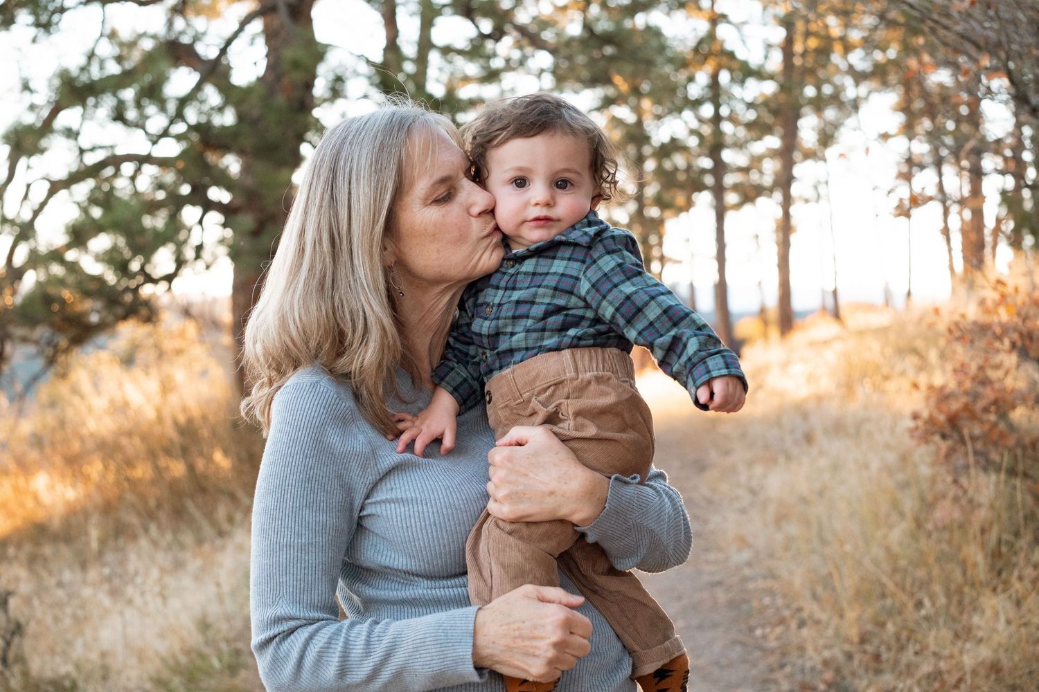 Grandmother kissing one year old grandson boy on the cheek.