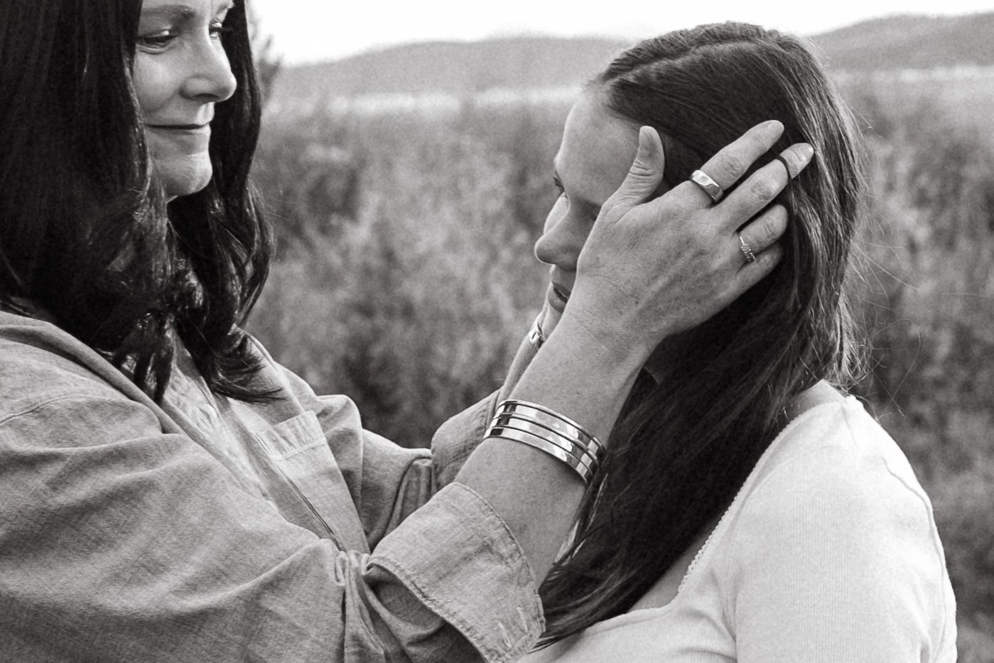 Black and white portrait of mother pushing daughter's hair out of her face.