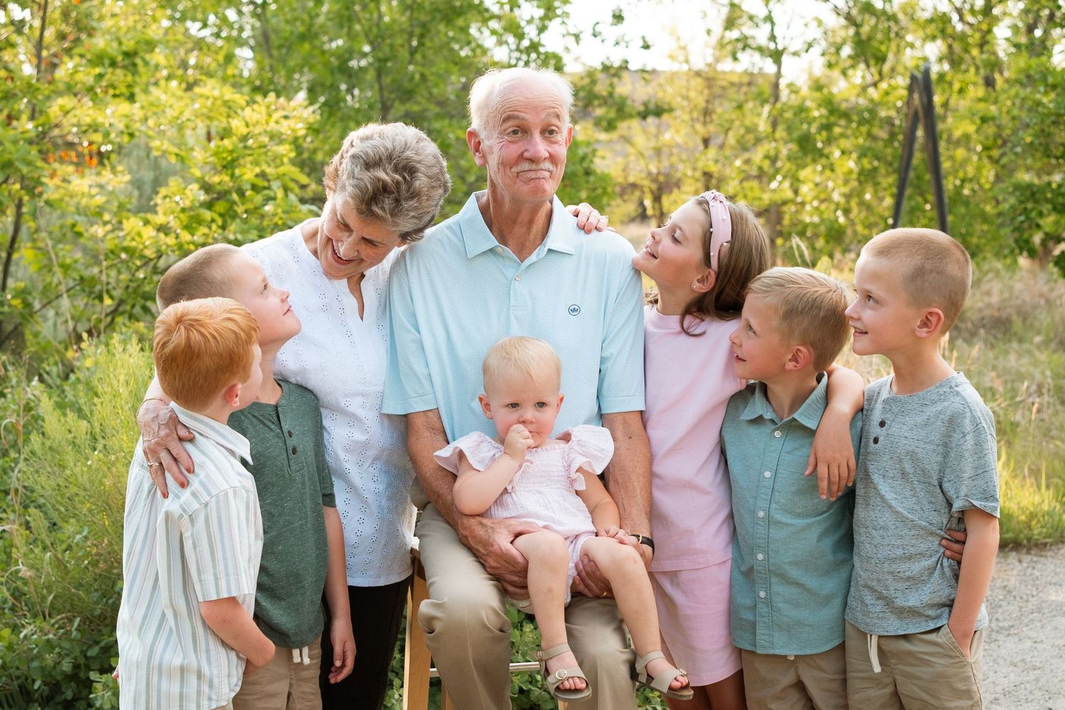 Close up candid of family during extended family photo session, all children looking toward grandpa, grandpa making a funny expression